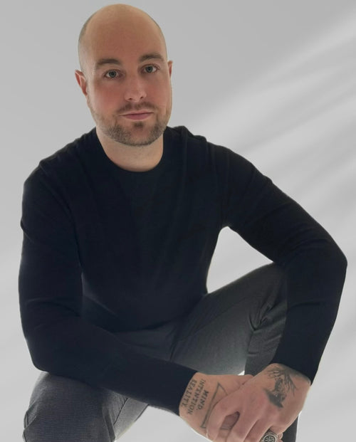 Portrait of JR, transformational coach, seated calmly in a minimalist setting